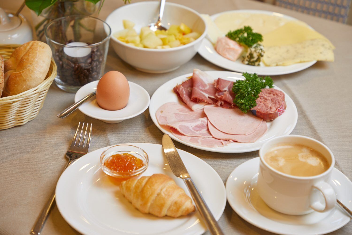 Desayuno con cruasanes, jamón, huevos y café.