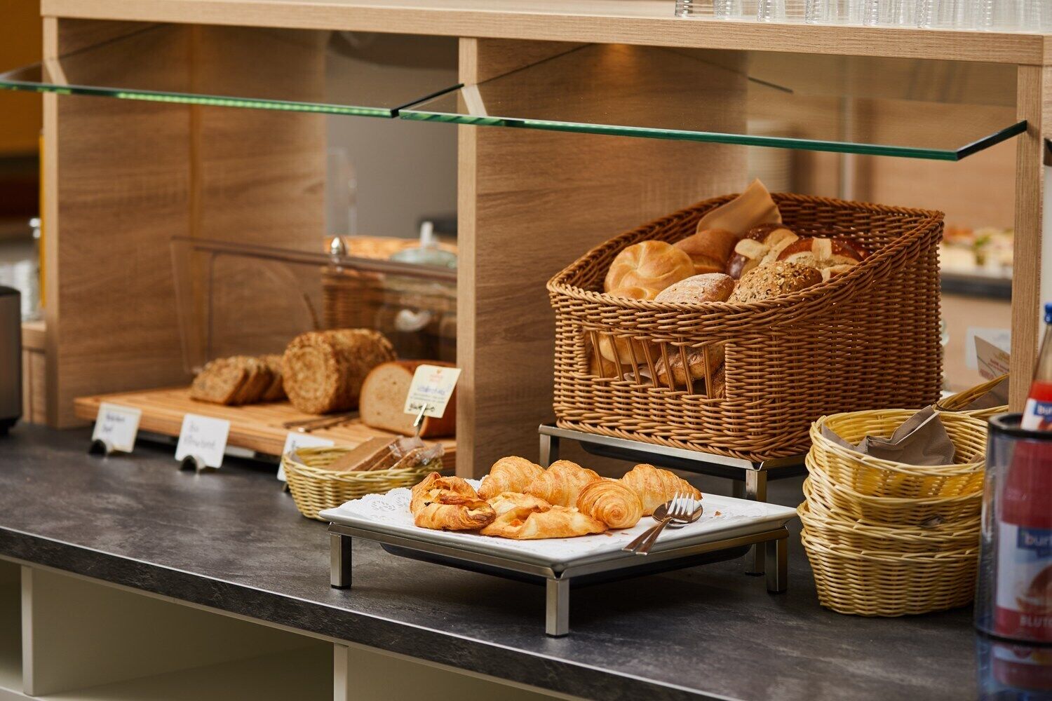 Balcão de buffet com diversos pães e doces expostos em cestas e num prato.