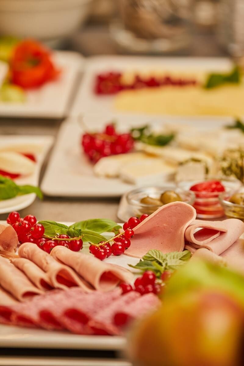 Diversos alimentos como carnes, quesos y frutas dispuestos en platos.
