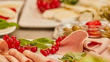 Diversos alimentos como carnes, quesos y frutas dispuestos en platos.