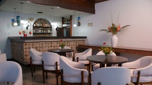 Een restaurant met een bar, witte stoelen en een kamerplant.