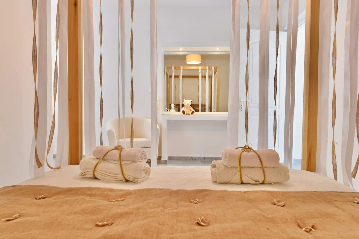 Ein Hotelzimmer mit einem großen Bett, einem Sessel, einem Schminktisch mit Spiegel und Handtüchern auf dem Bett.