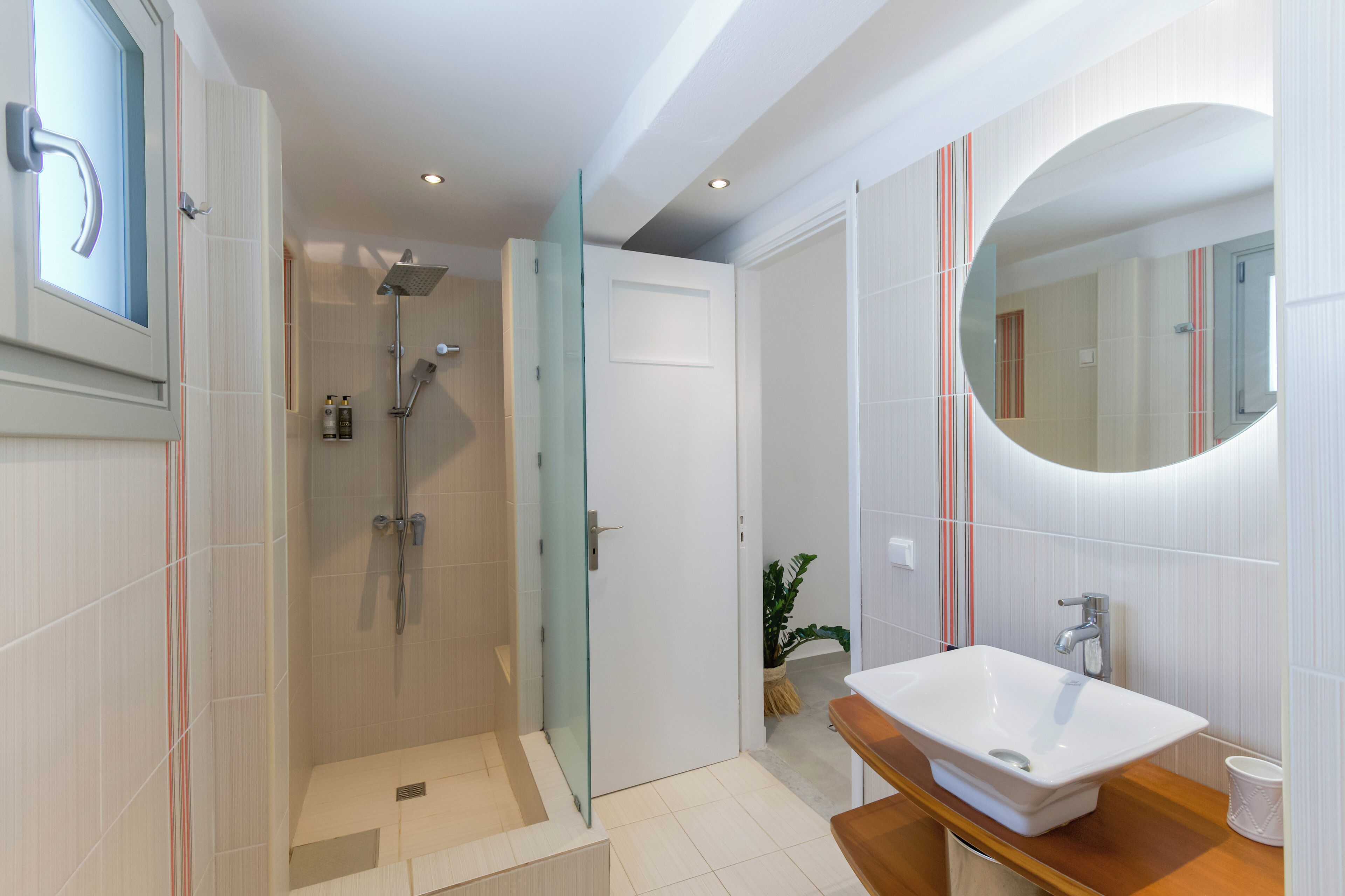 A modern bathroom with a glass-enclosed shower, a white sink, and a large mirror.