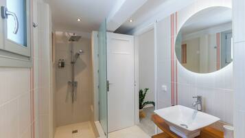 A modern bathroom with a glass-enclosed shower, a white sink, and a large mirror.