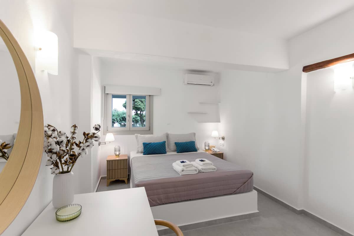 Ein modernes Schlafzimmer mit Bett, Nachttischen, einem Schreibtisch und einem Spiegel.