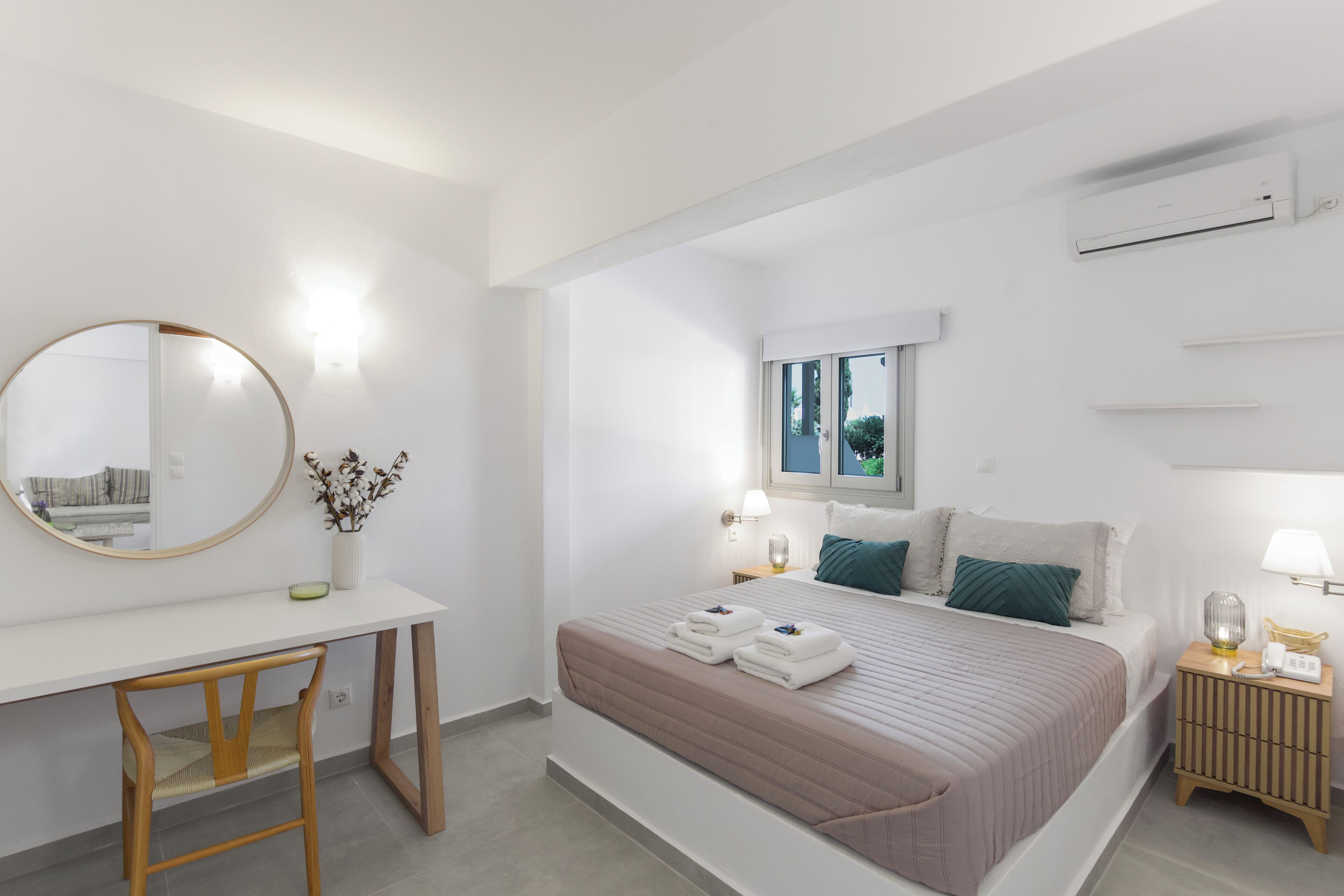 Ein modernes Hotelzimmer mit Bett, Nachttischen, einem Schreibtisch und einem Sessel.