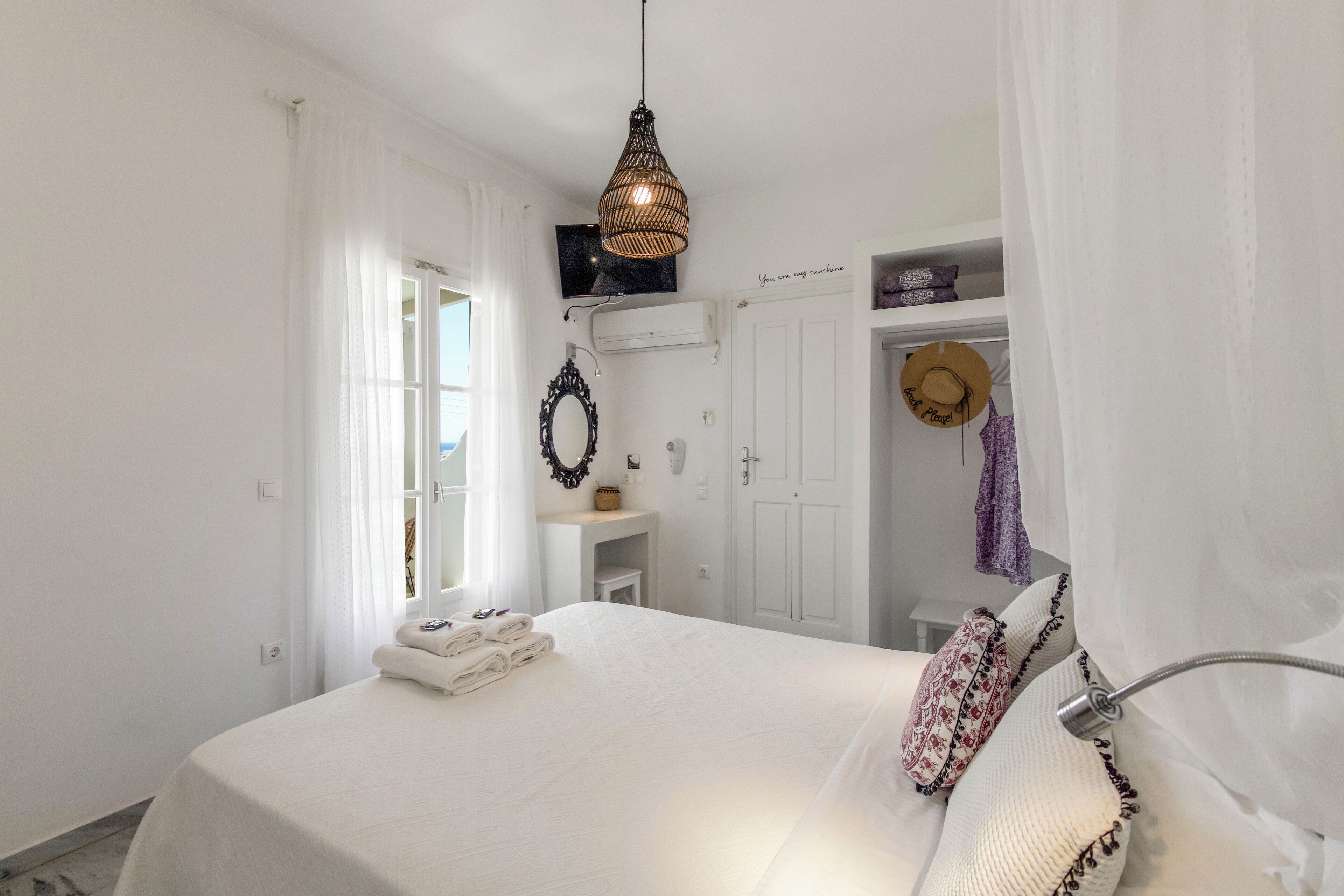 Un dormitorio con una cama, una lámpara colgante, un tocador con espejo y una puerta con toallero.