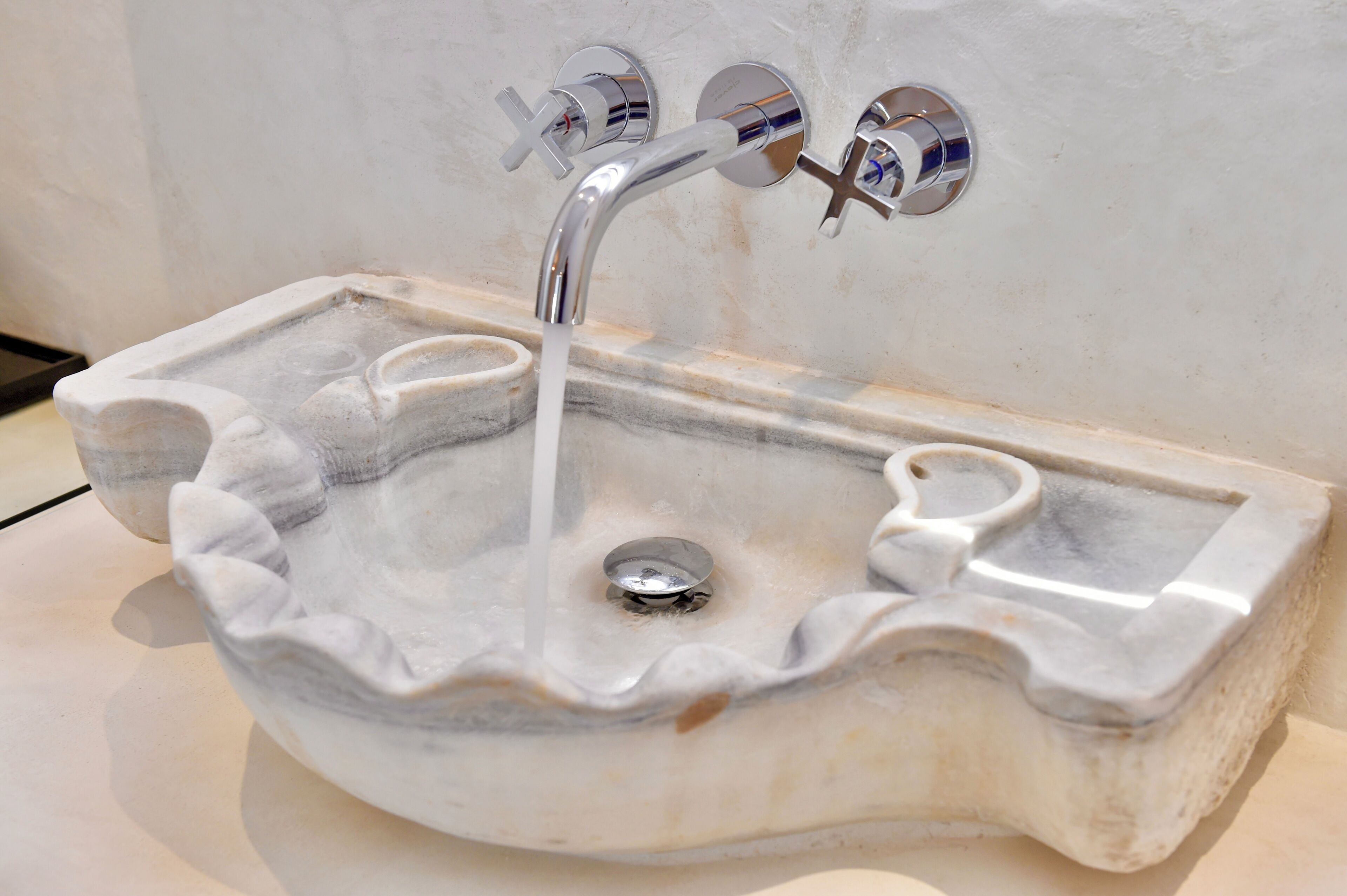 A marble sink with a single faucet and a drain.