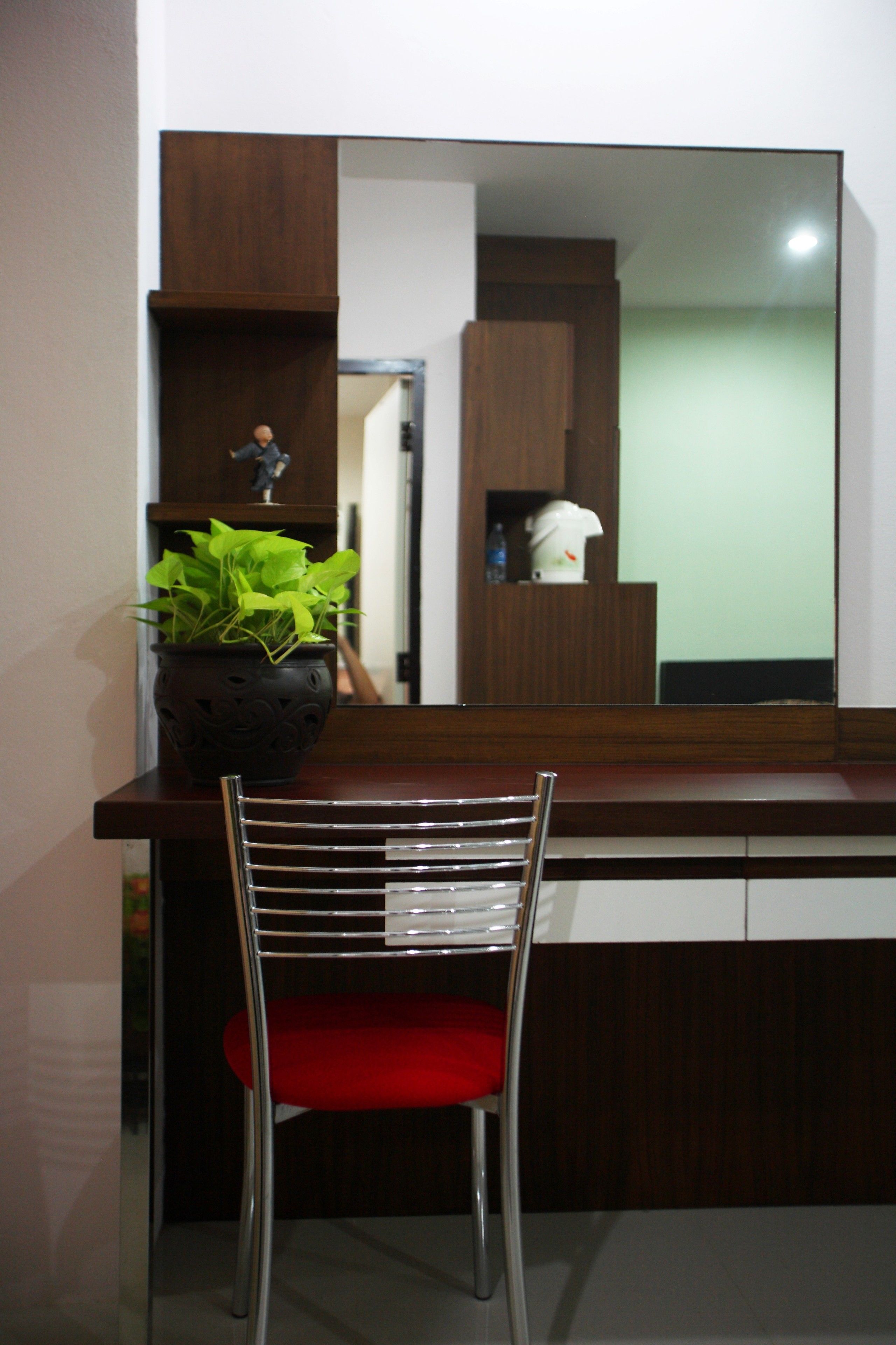 Una cocina moderna con encimera de madera, una silla tapizada en rojo y una planta en maceta.
