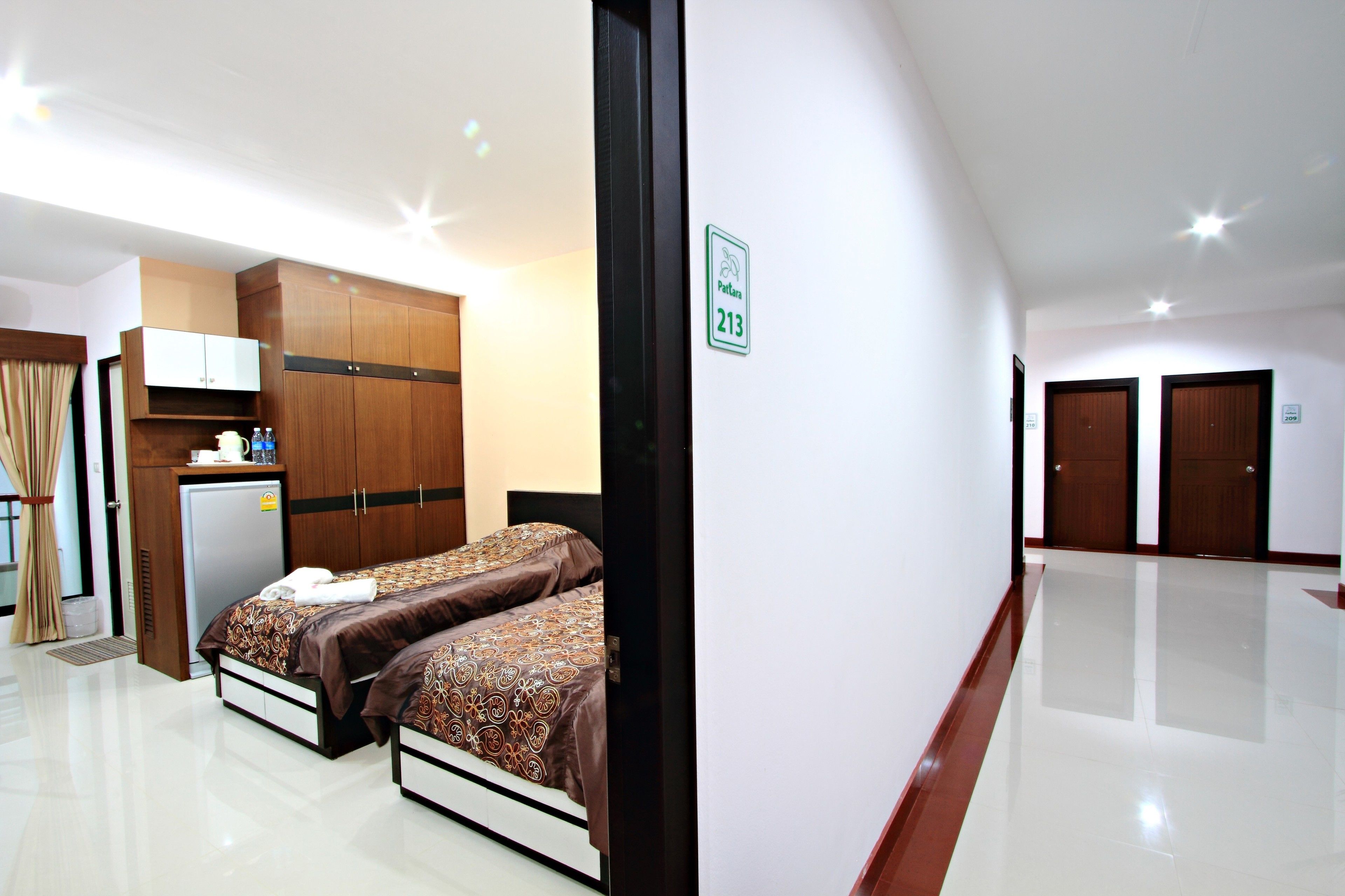 A hotel room with two beds, a kitchenette, and a bathroom.