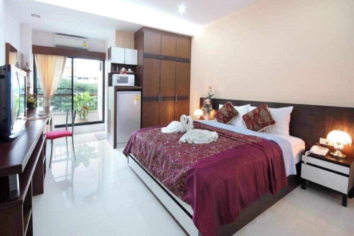 A hotel room with a bed, bedside table, desk, and a view of the outdoors.