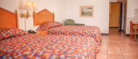 A hotel room with two beds, a chair, a desk, and a painting on the wall.