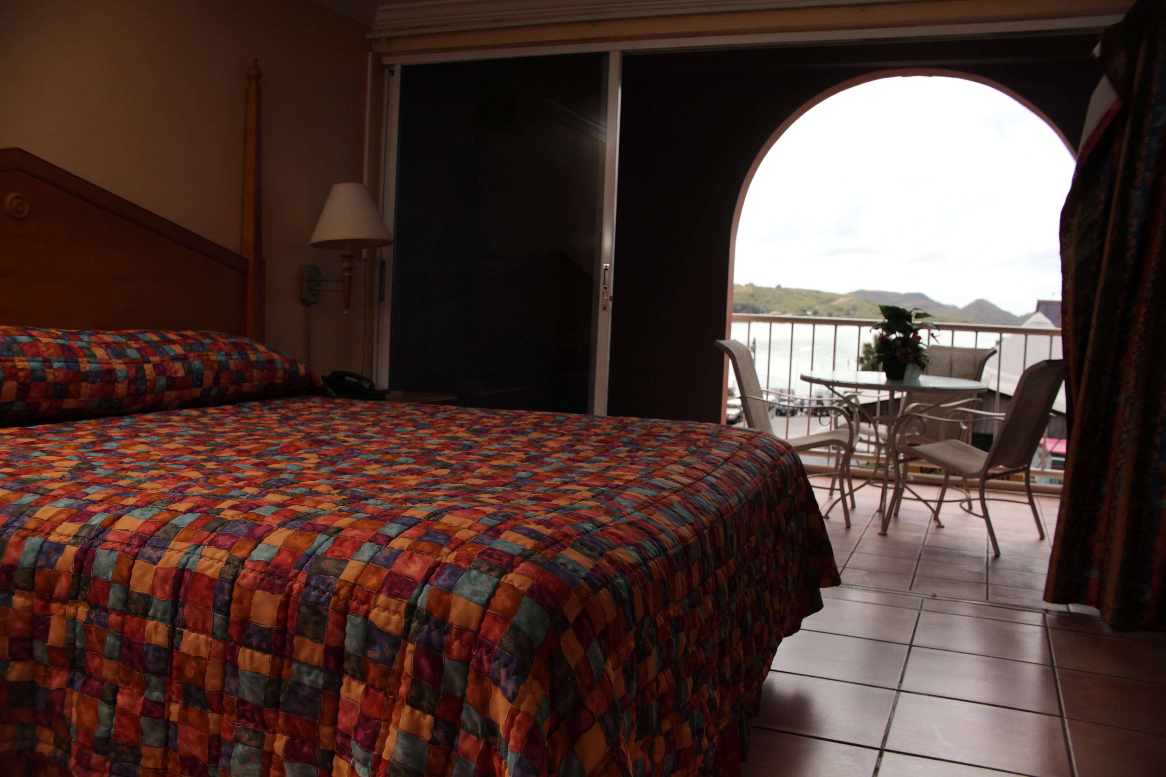 Une chambre d’hôtel avec un grand lit, un balcon avec une table et des chaises, et une vue sur la mer.