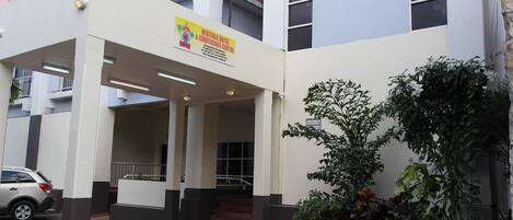 A hotel entrance with a sign for Heritage Hotel & Conference Centre, featuring a covered entrance, stairs, and a parking area.