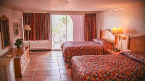 Een hotelkamer met twee bedden, een bureau, een stoel en een balkon met een tafel en stoelen.