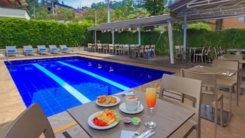 Relax by the serene pool, surrounded by lush greenery and a shaded seating area.