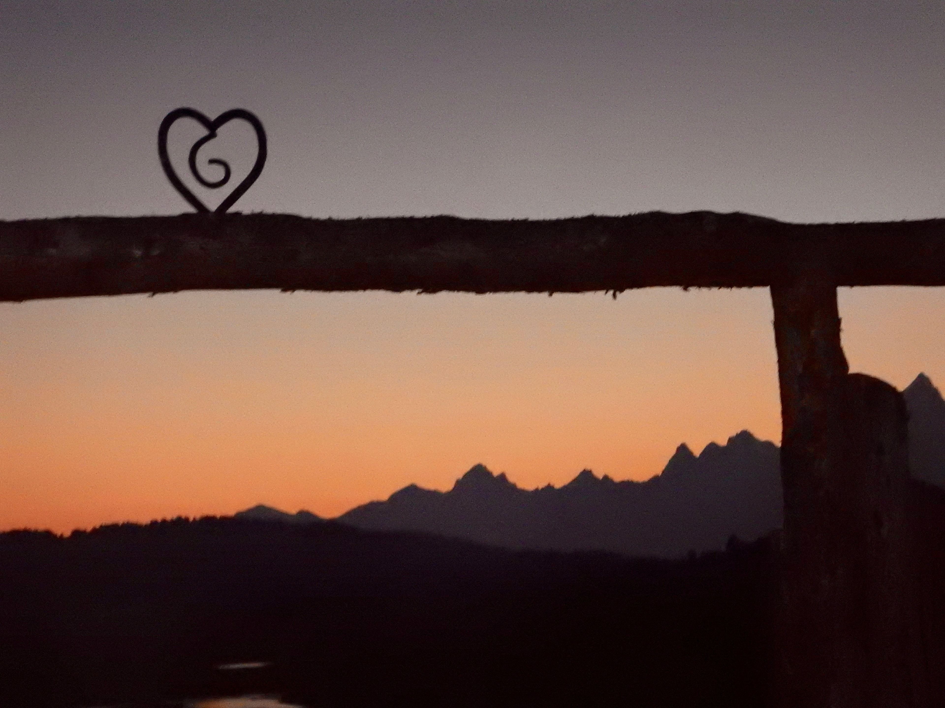 A sunset with a heart-shaped decoration on a fence.