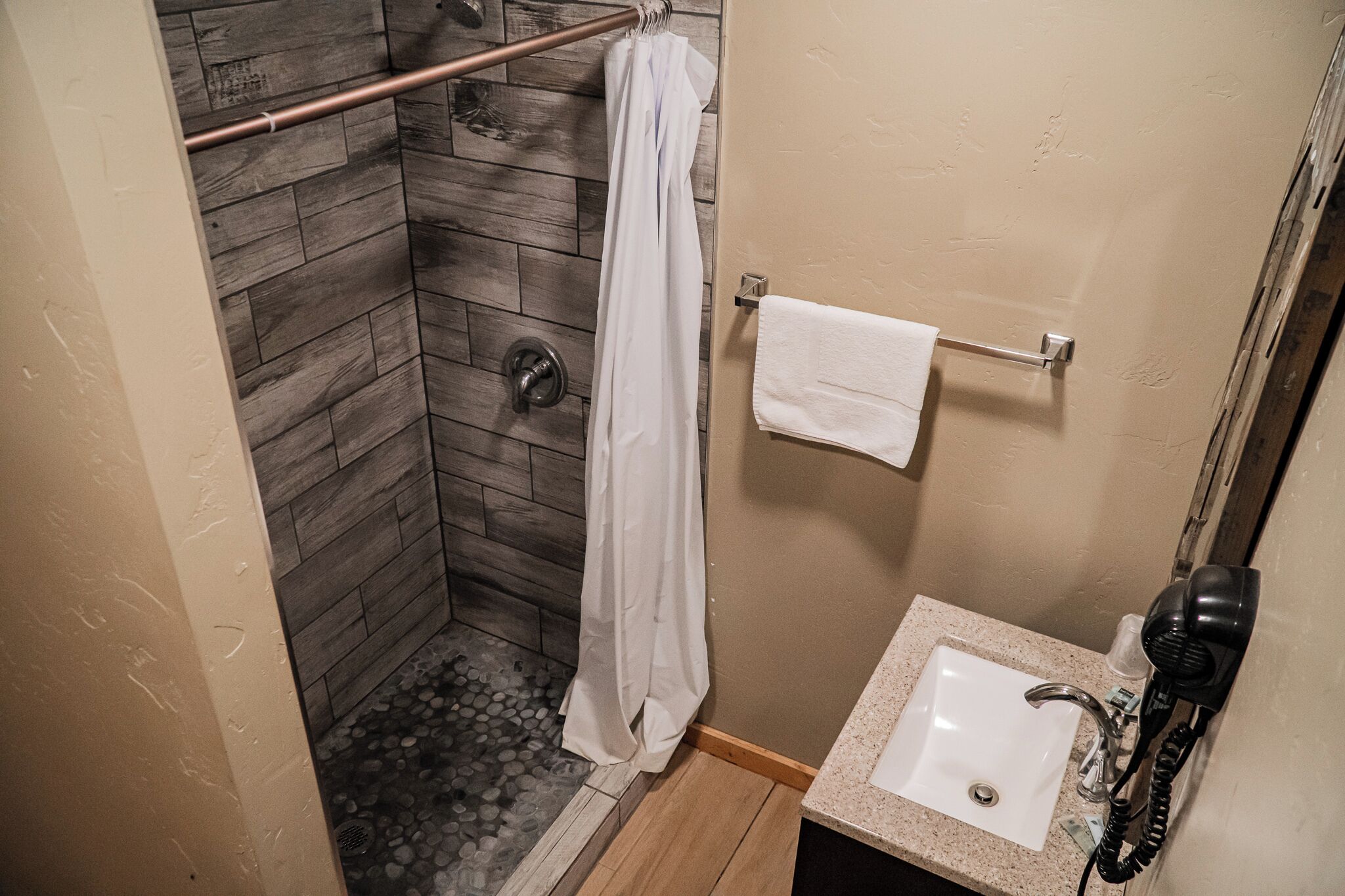 Un baño pequeño con ducha, lavamanos y secador de pelo.