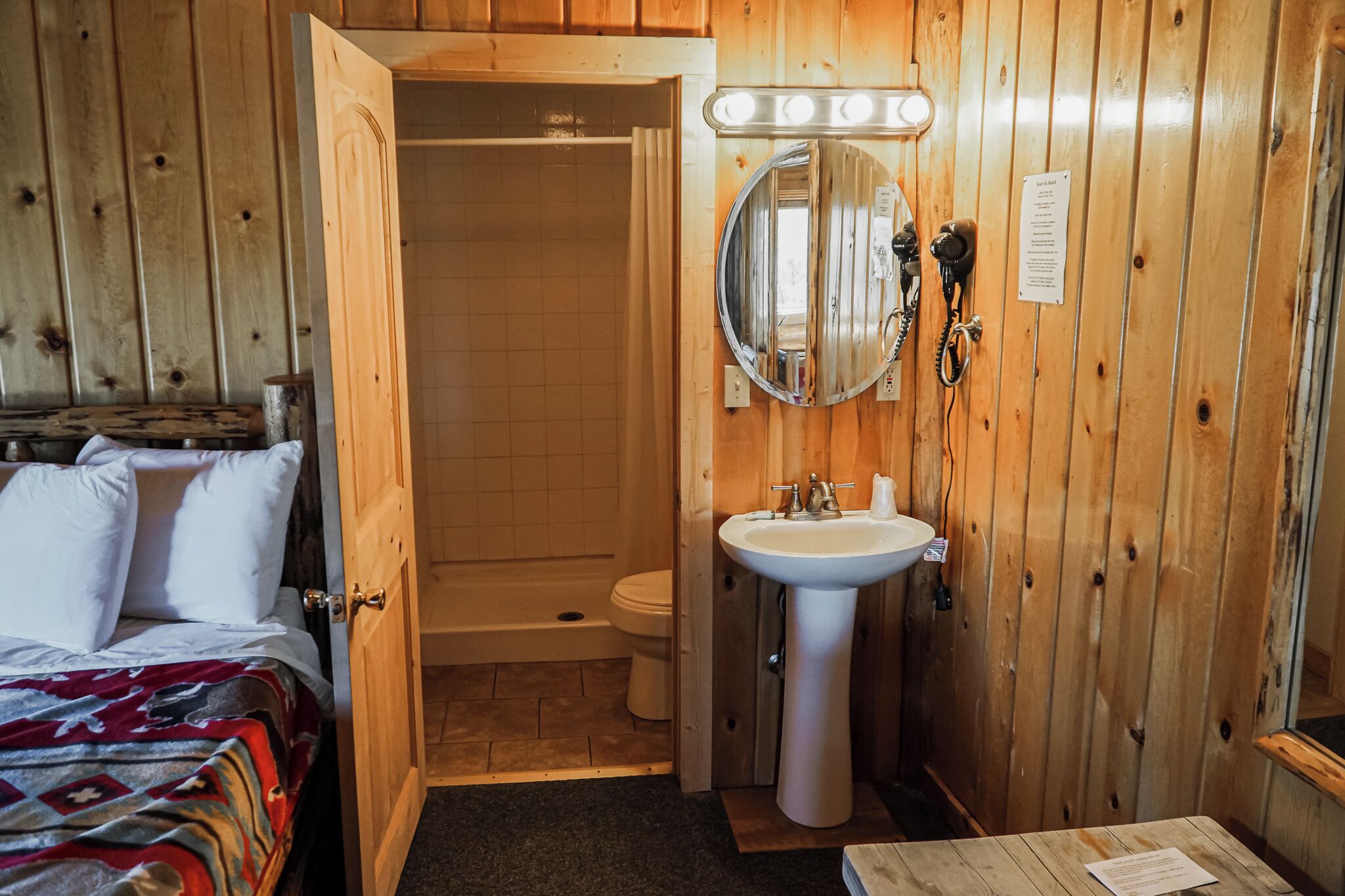 A wooden-paneled bathroom with a sink, mirror, and toilet.