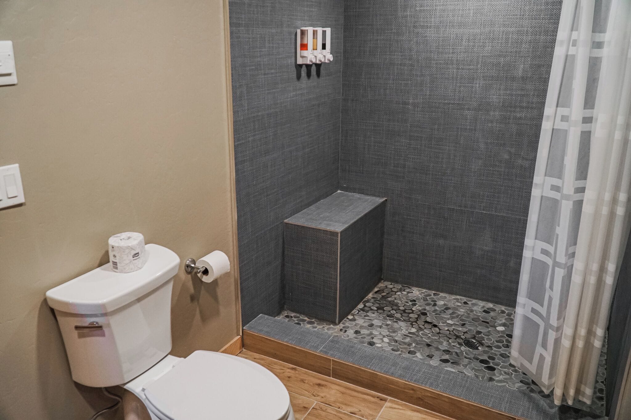 Ein Badezimmer mit Toilette, einer Duschkabine und einem kleinen Stauraum.
