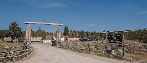 Una rústica puerta de madera con un letrero que anuncia Heart Six Guest Ranch, indicando habitaciones y cabañas.