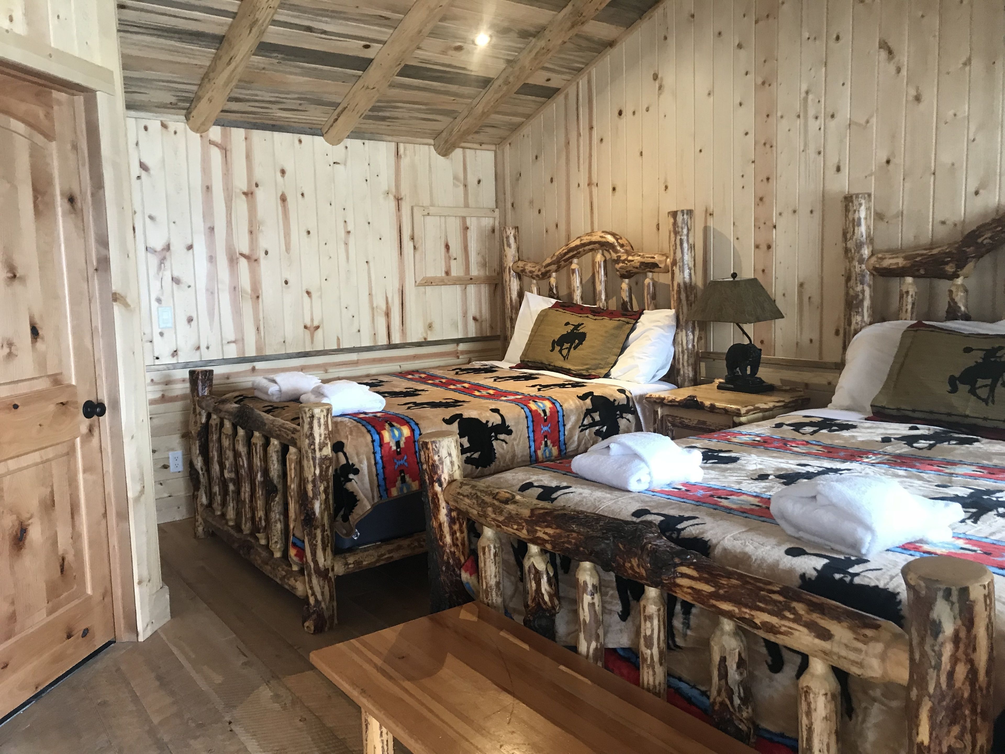 A rustic wooden room with a bed, bench, and a wooden door.