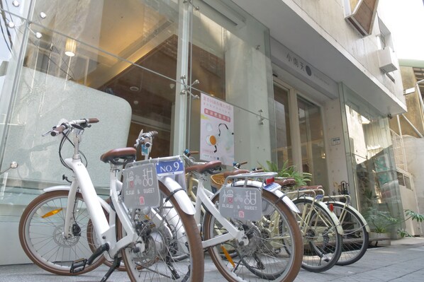 Bicycles parked in front of a building with glass doors and a sign indicating a number 9 parking spot. - SSS Life Hotel (Tainan)