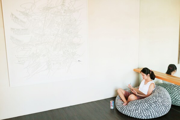 A person sitting on a bean bag chair in a room with a large abstract drawing on the wall.