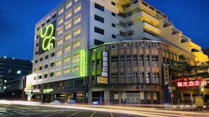A multi-story hotel with a prominent green logo, multiple balconies, and a variety of signage indicating different services and amenities. - Park City Central (Taichung)