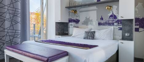 Un dormitorio moderno con una cama grande, un banco y una pared decorada con motivos urbanos.