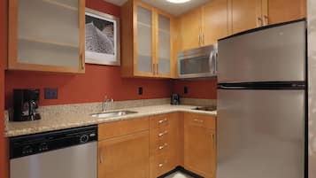 A kitchen with wooden cabinets, a stainless steel refrigerator, a microwave, and a dishwasher.