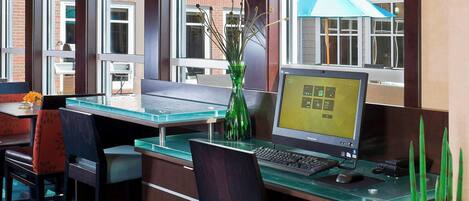 A modern office space with a glass desk, multiple chairs, and a laptop.