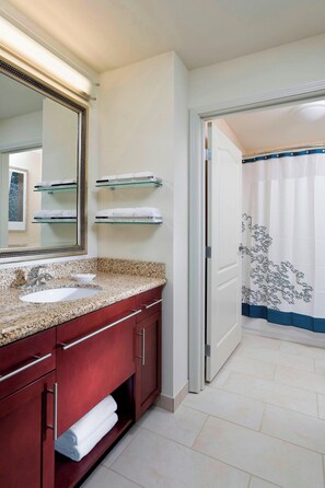 A bathroom with a granite countertop, a sink, a mirror, and a towel rack. - Residence Inn Bismarck North (Bismarck)