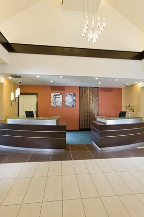 A hotel reception area with two reception desks, a modern chandelier, and artwork on the walls. - Residence Inn Bismarck North (Bismarck)