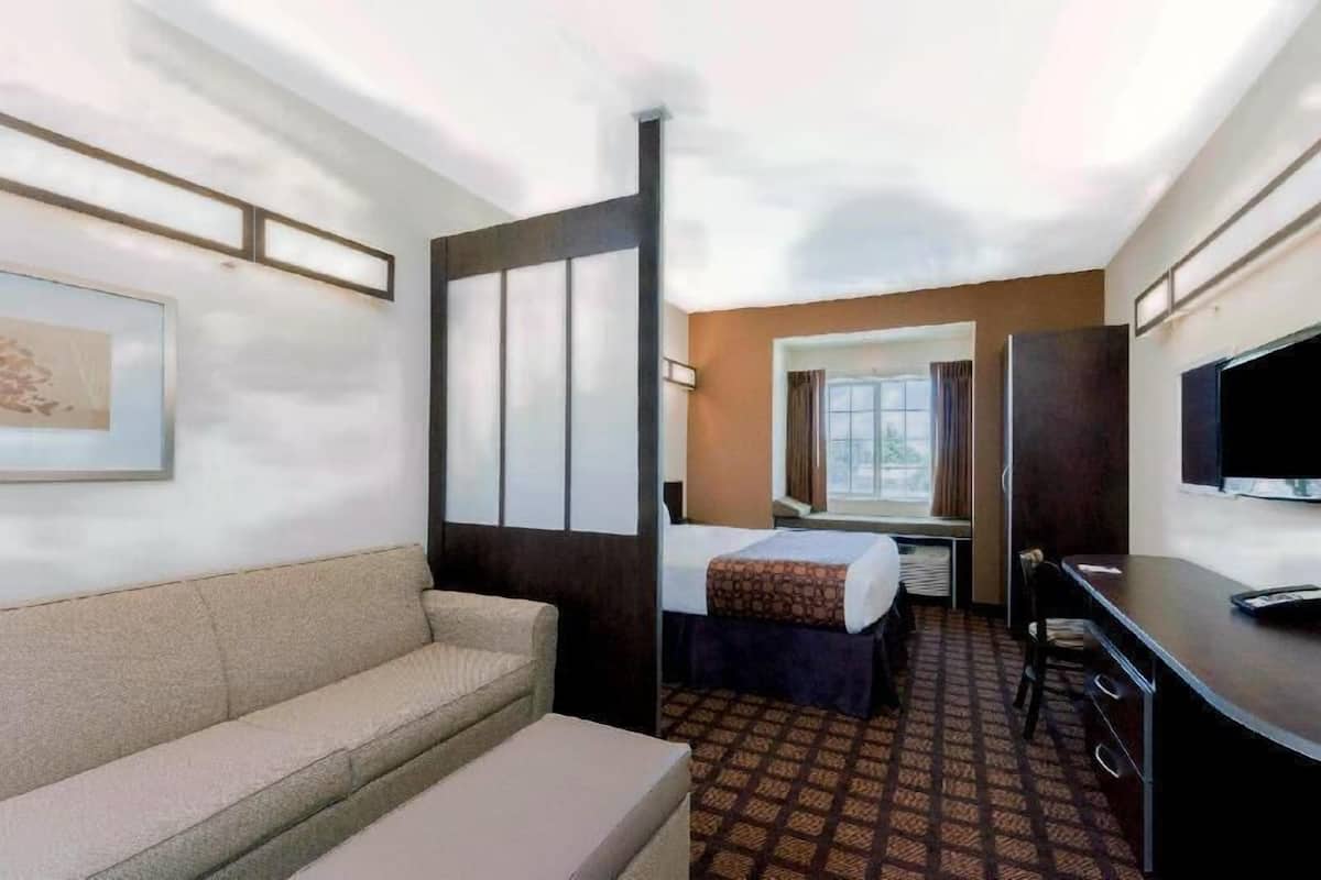 Una habitación de hotel con sofá, cama, escritorio y televisor.