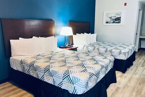 A hotel room with two beds, a nightstand with a lamp, and a framed picture on the wall. - Baymont by Wyndham Ridgecrest (Ridgecrest)