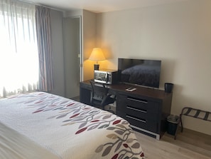 A hotel room with a bed, a desk with a TV, a lamp, and a chair. - Red Roof Inn Pittsburgh - McKnight Rd (Pittsburgh)