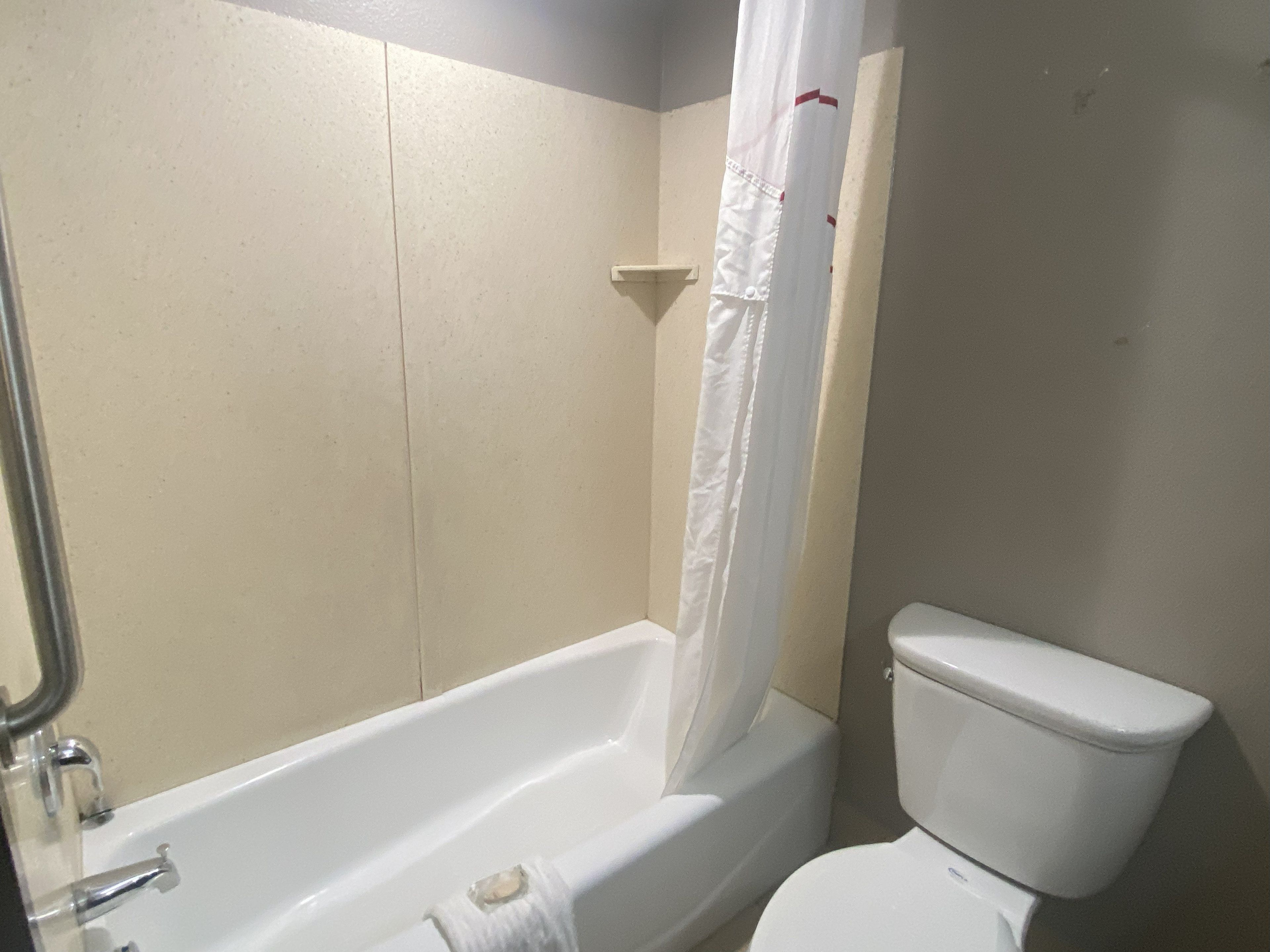 A bathroom with a bathtub, toilet, and shower curtain.