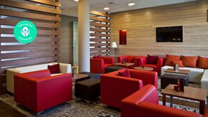 A modern lounge area with red and white seating, a patterned rug, and a wooden wall with a mounted TV. - Campanile Wroclaw Centrum (Wroclaw)