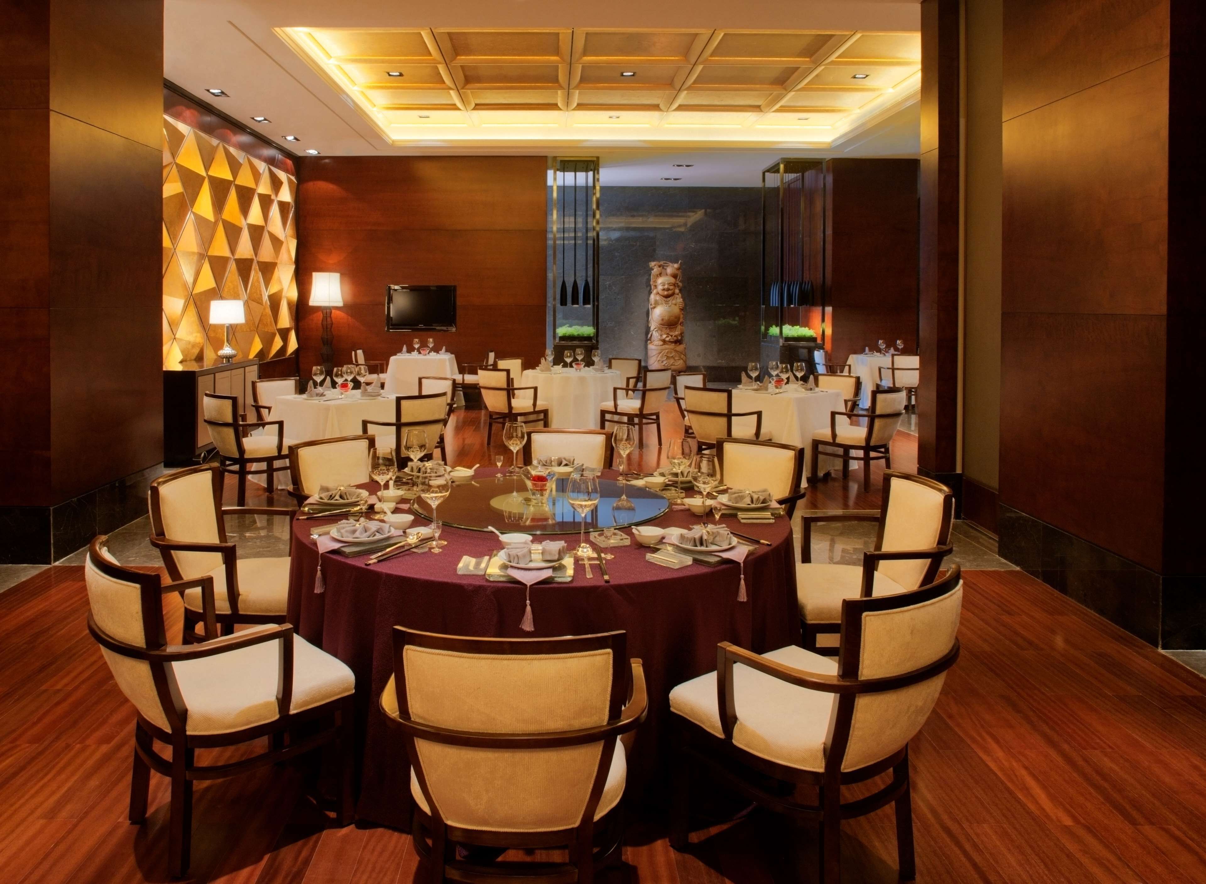 A conference room with round tables, chairs, and a television screen.