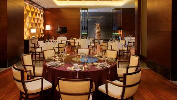 A conference room with round tables, chairs, and a television screen.