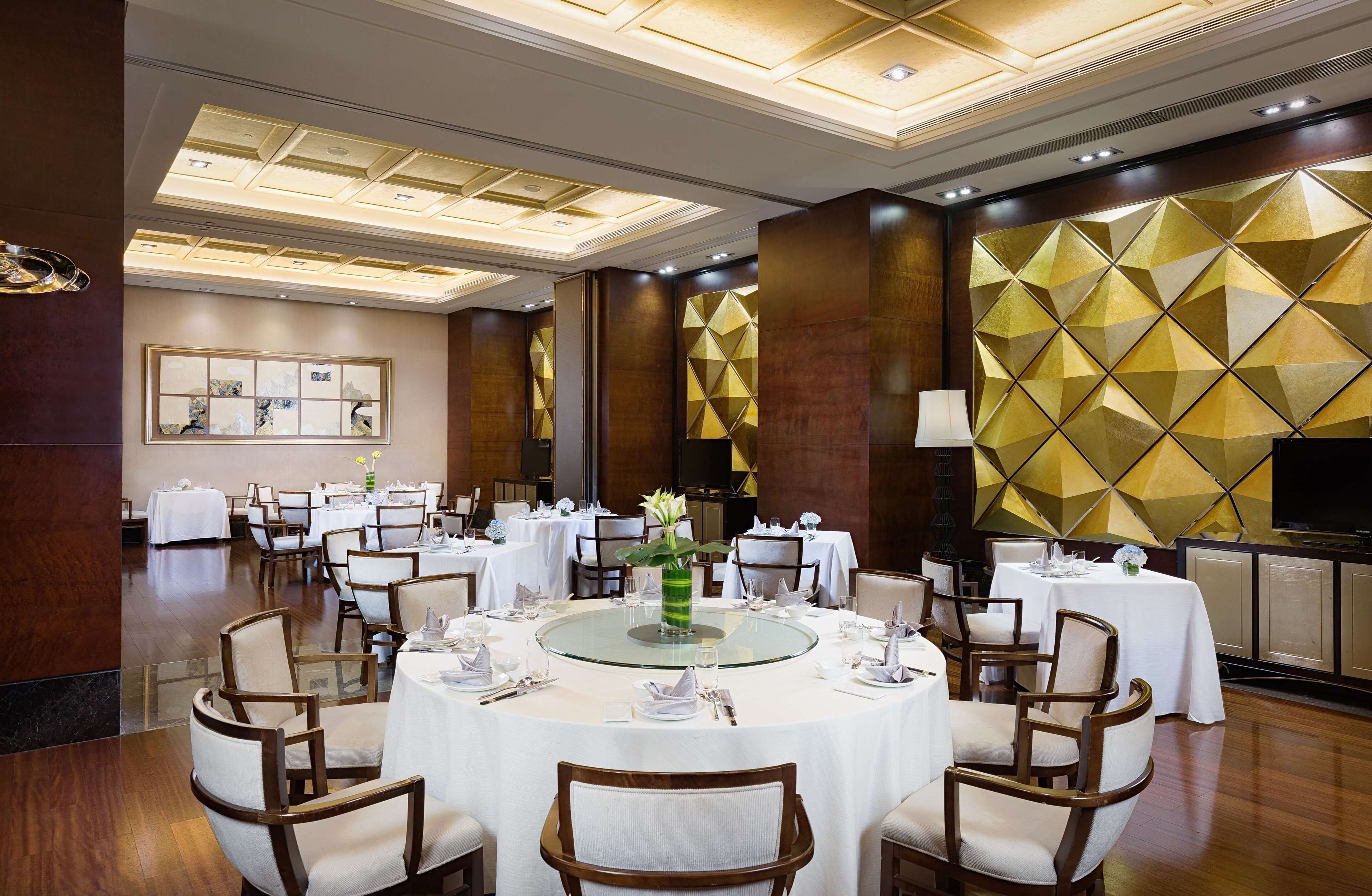 Un comedor de hotel con mesas redondas, sillas y un arreglo floral central.