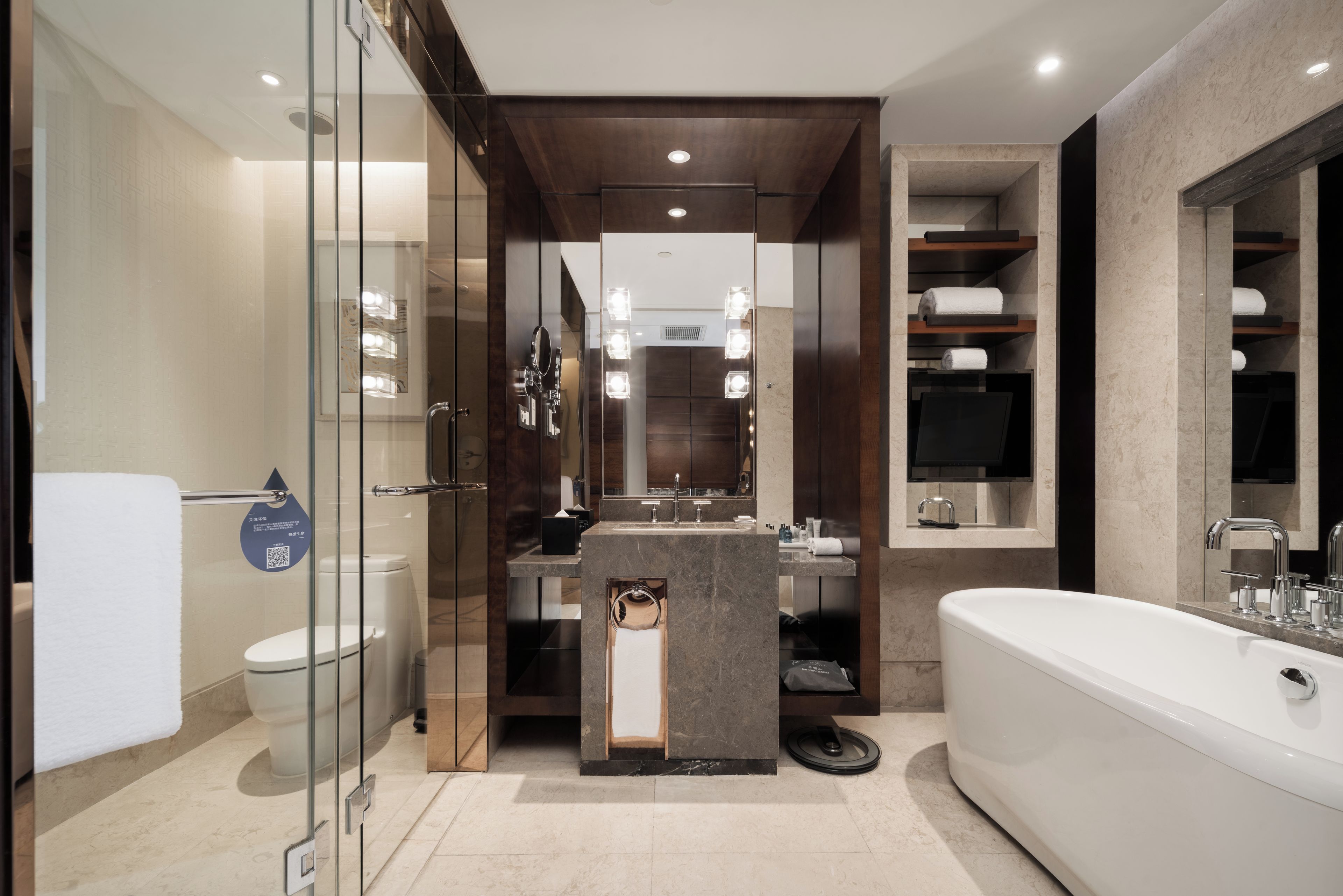 Un baño moderno con ducha envuelta en vidrio, una bañera independiente y un tocador con encimera de mármol.