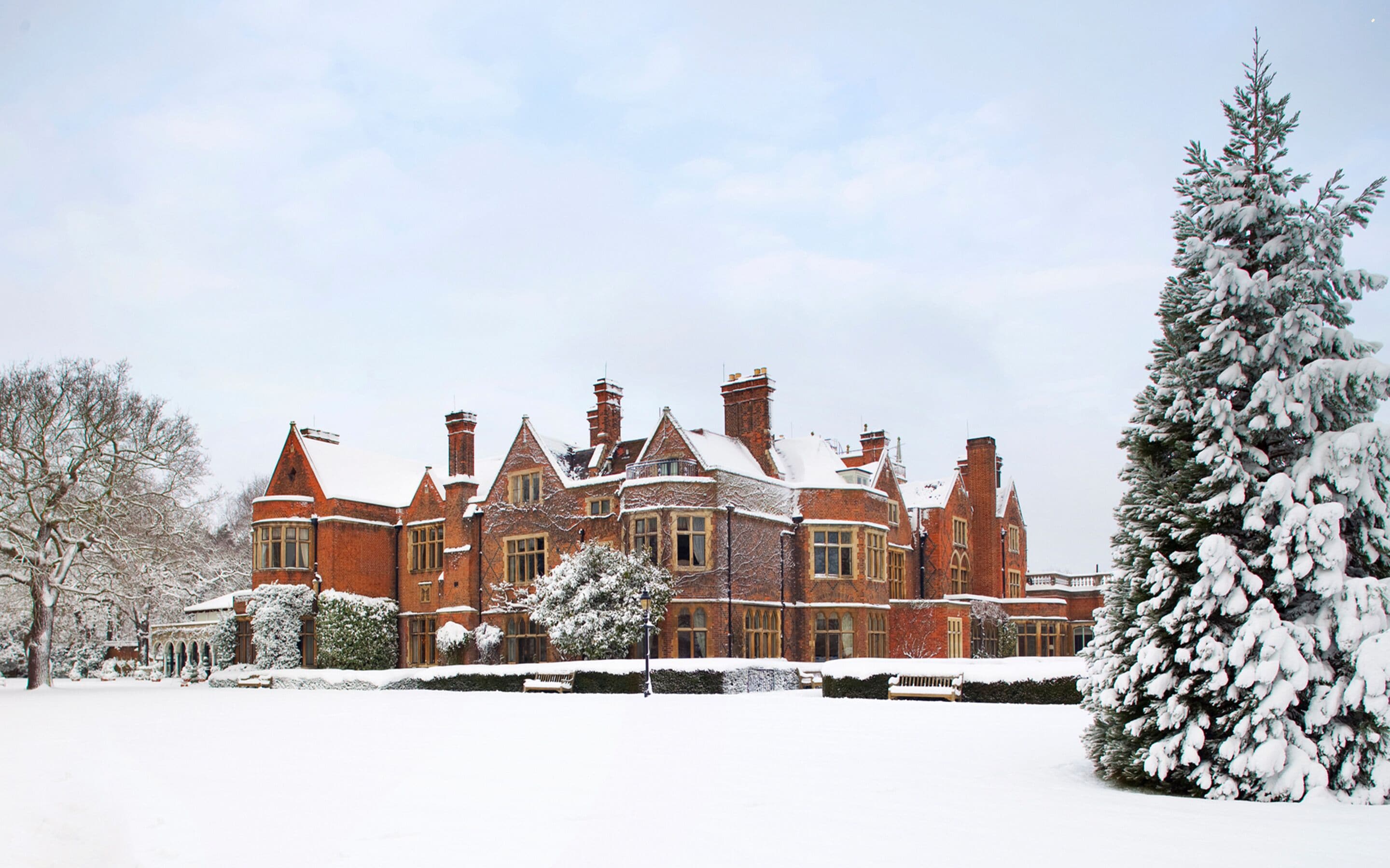 A large, historic building with multiple chimneys and a snow-covered landscape.