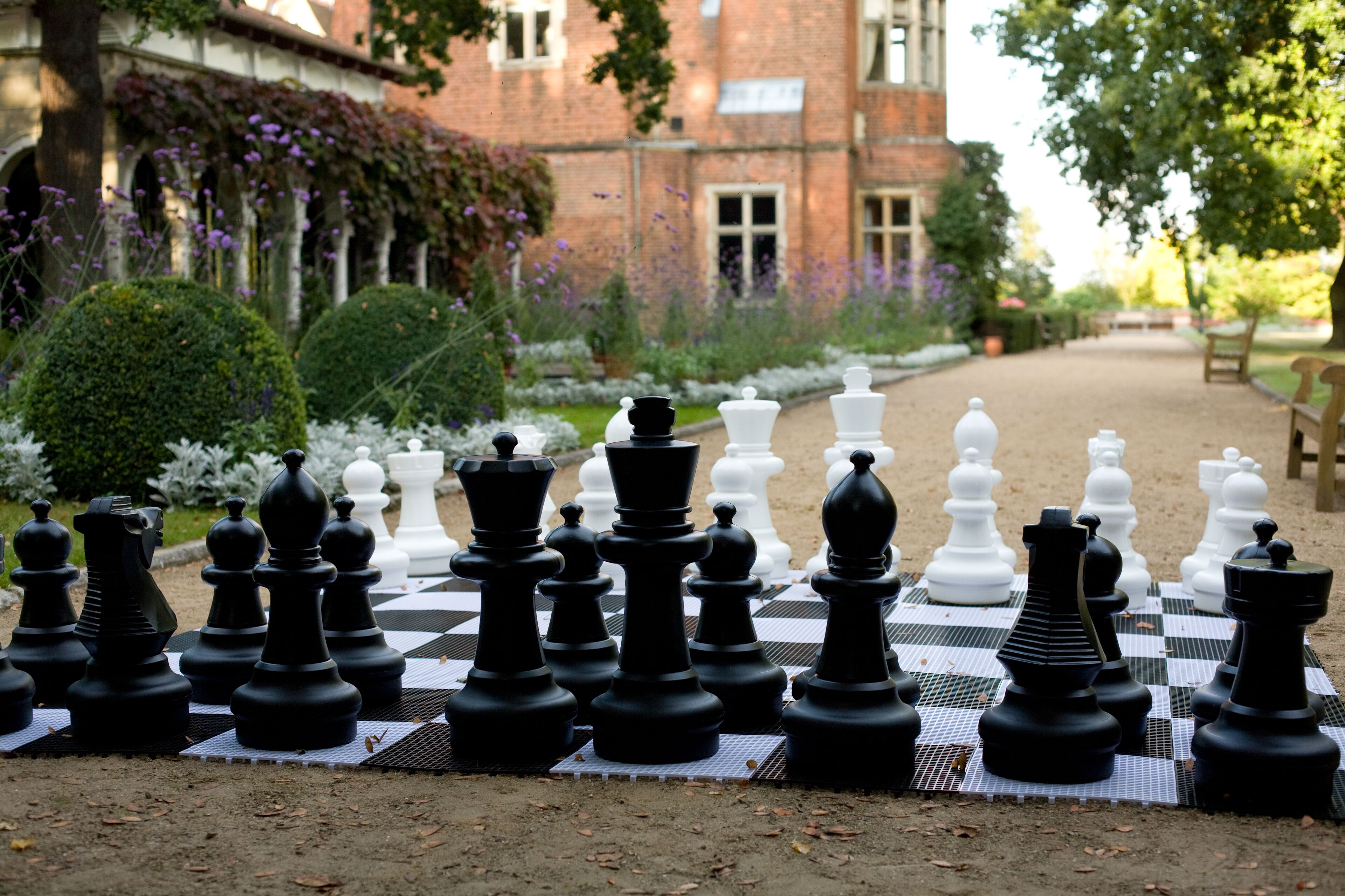 A chessboard set up outdoors with a building in the background.