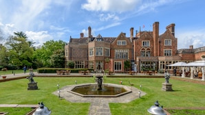 A large brick building with a central fountain, surrounded by a well-maintained lawn and outdoor seating areas. - Warren House (Kingston Upon Thames)