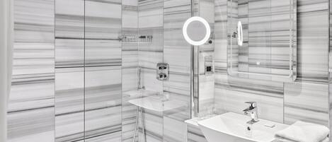 A modern bathroom with a glass shower enclosure, a vanity with a sink, and a large mirror.