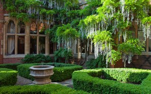 A courtyard with a fountain, trimmed hedges, and hanging white flowers. - Warren House (Kingston Upon Thames)