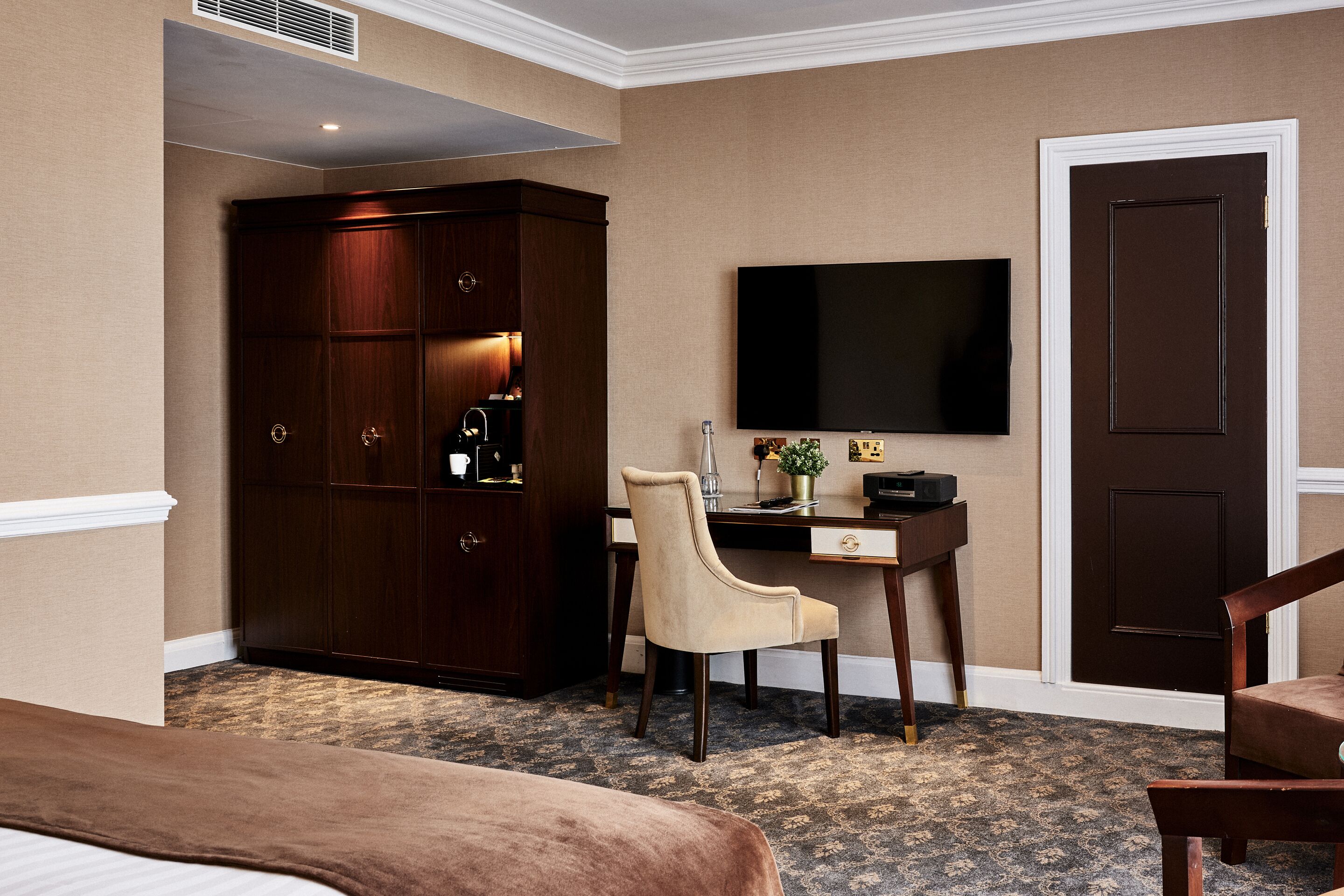 Une chambre d’hôtel comprenant un grand placard, un bureau avec une chaise, un téléviseur à écran plat et un lit.