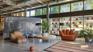A spacious indoor area with a basketball court, seating areas, and a wall with basketballs.